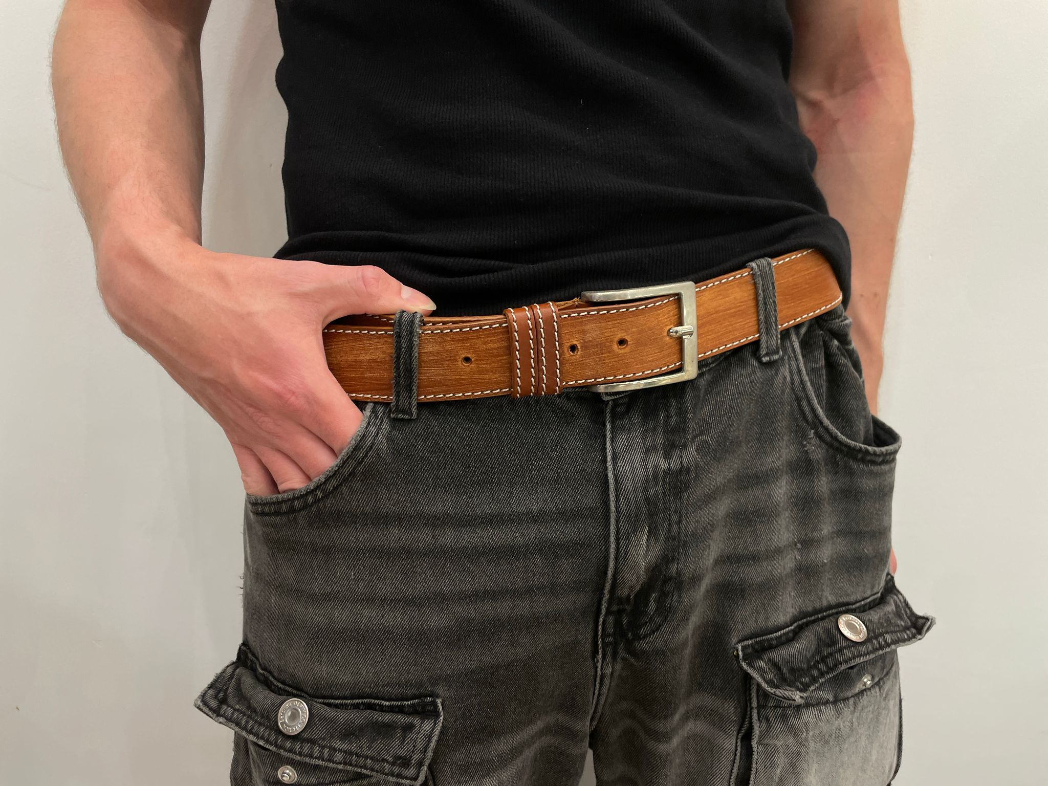 Unisex leather belt with distressed finish and stitched edges, showcasing a stylish and rugged design.