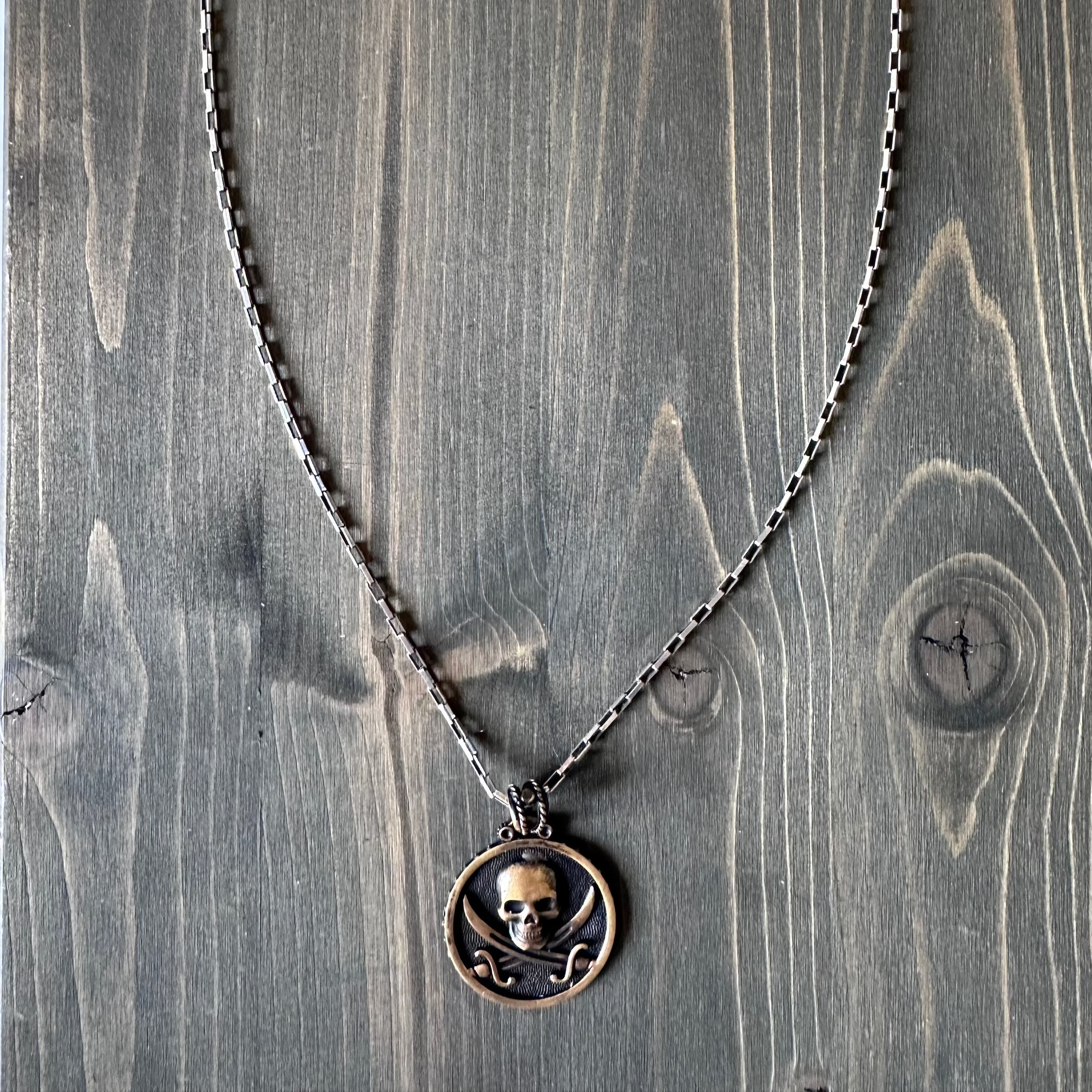 Silver and bronze pirate-themed necklace featuring a skull pendant and black sails design by BDG Accessories.