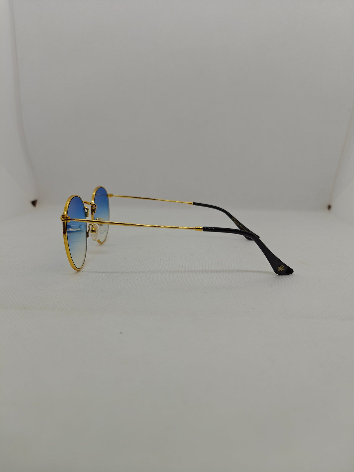 Occhiali da sole rotondi Sbarià Catania con montatura dorata in alpacca e lenti sfumate blu, vista laterale