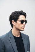 Uomo indossa occhiali da sole rotondi Sbarià con montatura sottile in metallo nero e lenti scure, stile elegante.